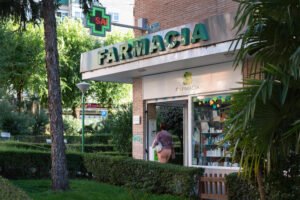 Fachada de una farmacia en España con cruz verde luminosa