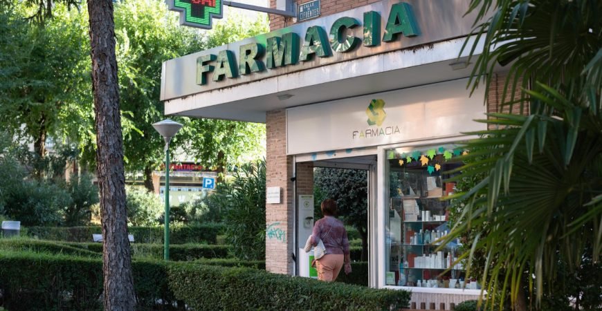 Fachada de una farmacia en España con cruz verde luminosa